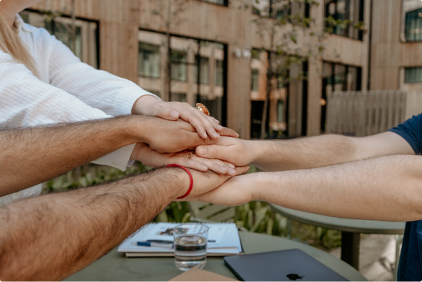 Several hands stacked on top of each other in unison