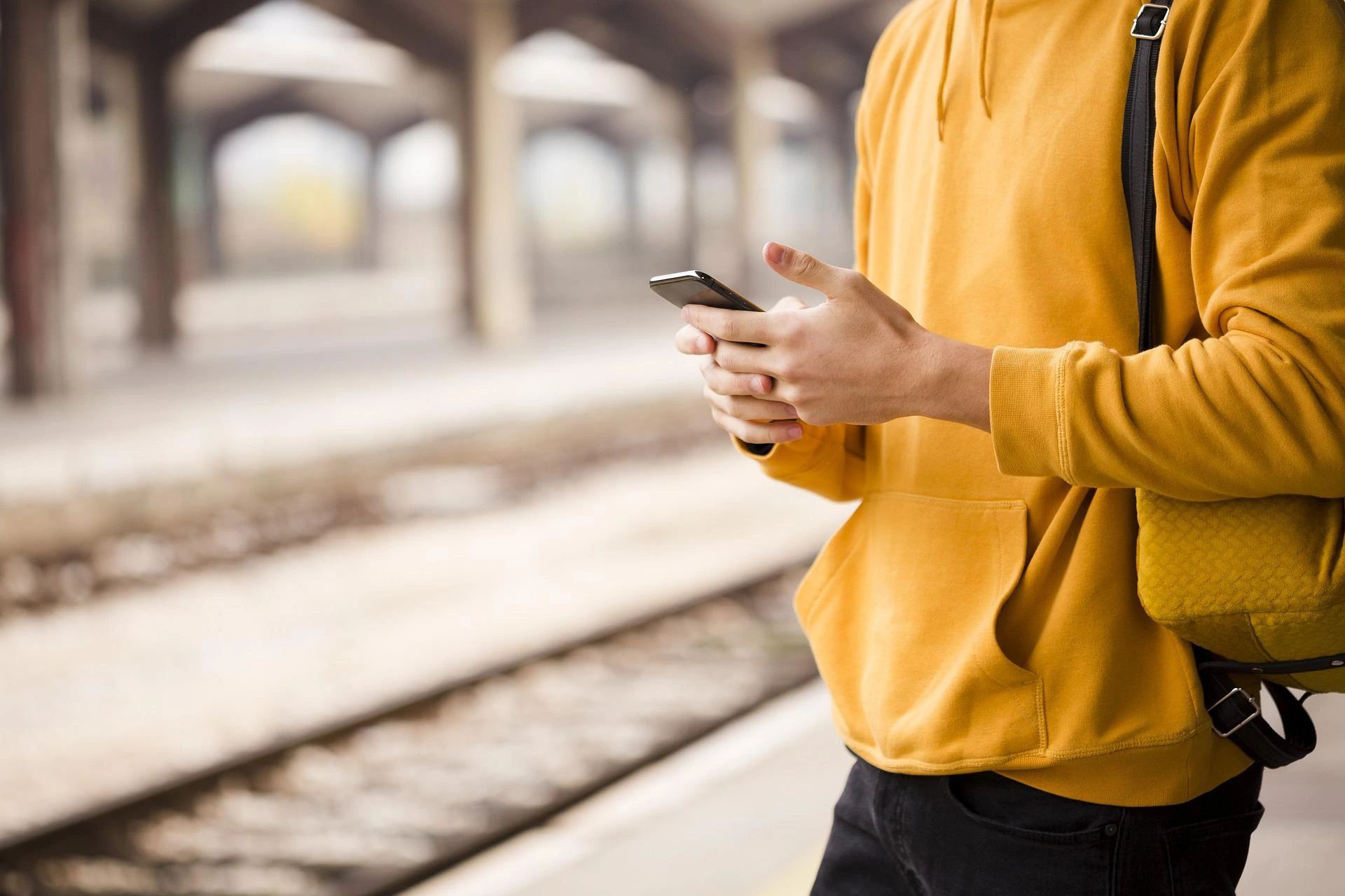 Man checking his phone at train station