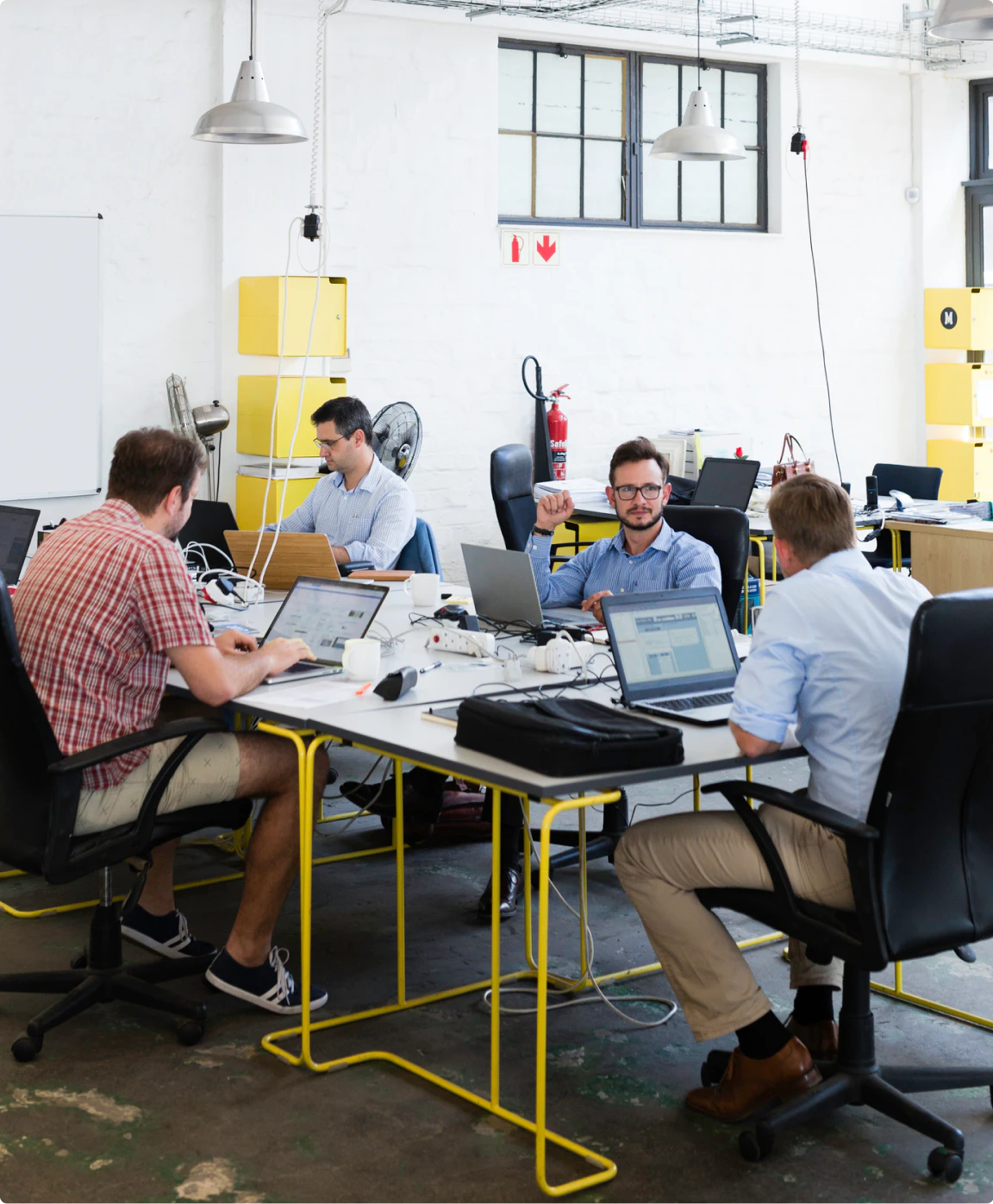 Image of a team of people working on computers, sitting around a desk. 